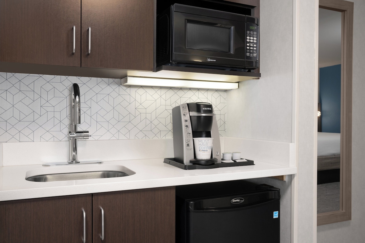 A compact kitchenette with a microwave, coffee maker, and dishwasher.