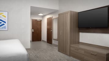 Habitación de hotel con cama, armario, televisor de pantalla plana y un pasillo que conduce a otra habitación.