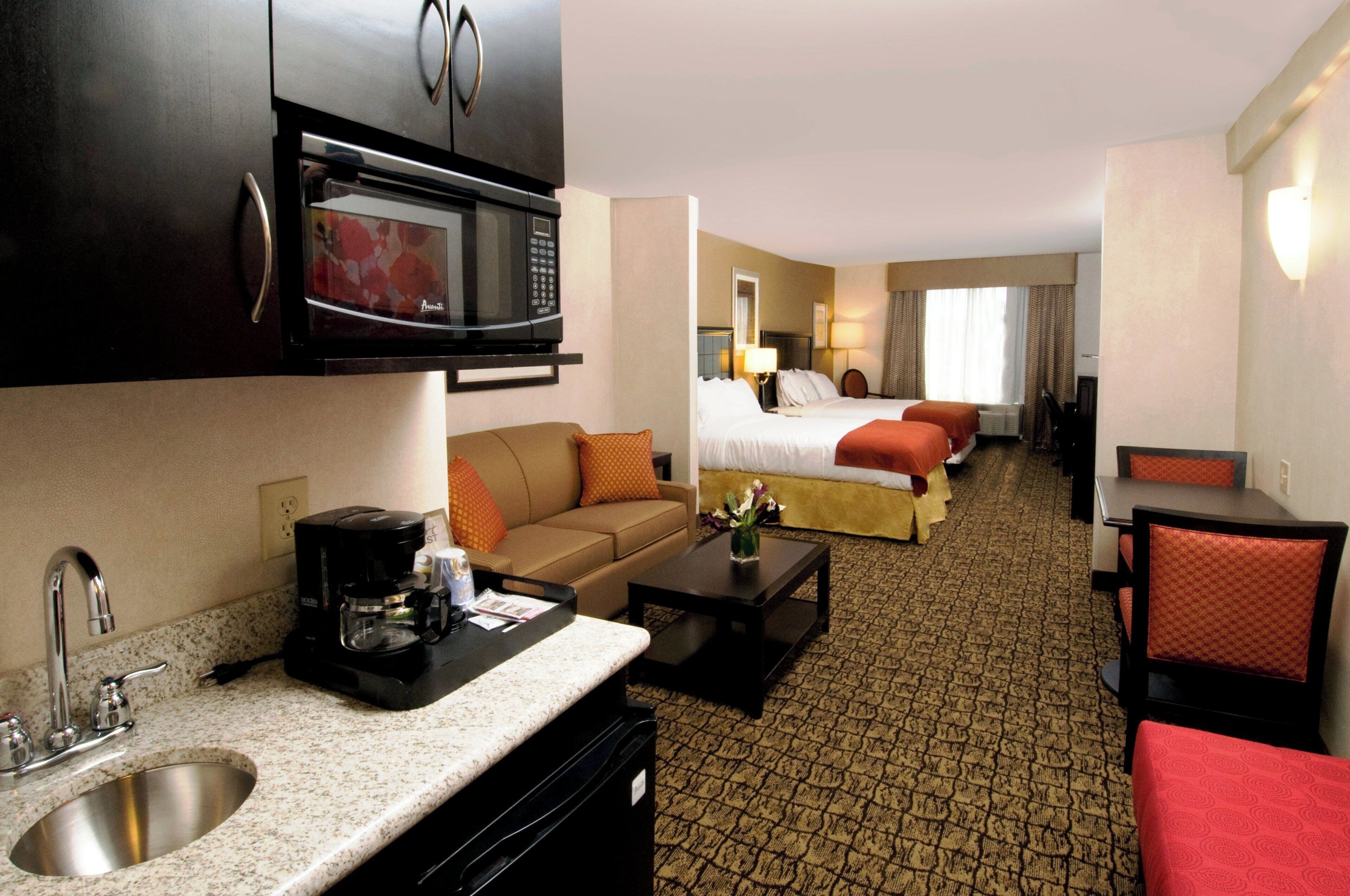 Une chambre d’hôtel équipée d’une kitchenette, d’un lit, d’un canapé, d’une table à manger et d’une salle de bain.