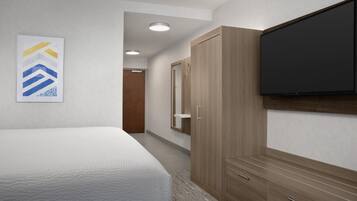 Ein Hotelzimmer mit Bett, Kleiderschrank, Fernseher und einer Tür zu einem anderen Raum.