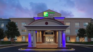 Un hotel Holiday Inn Express & Suites con una entrada moderna, amplias columnas y fachada bien iluminada.