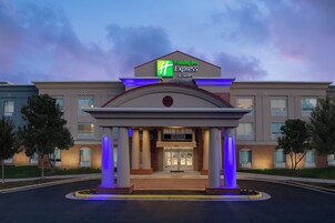 A Holiday Inn Express & Suites hotel with a modern entrance, large columns, and a well-lit facade.