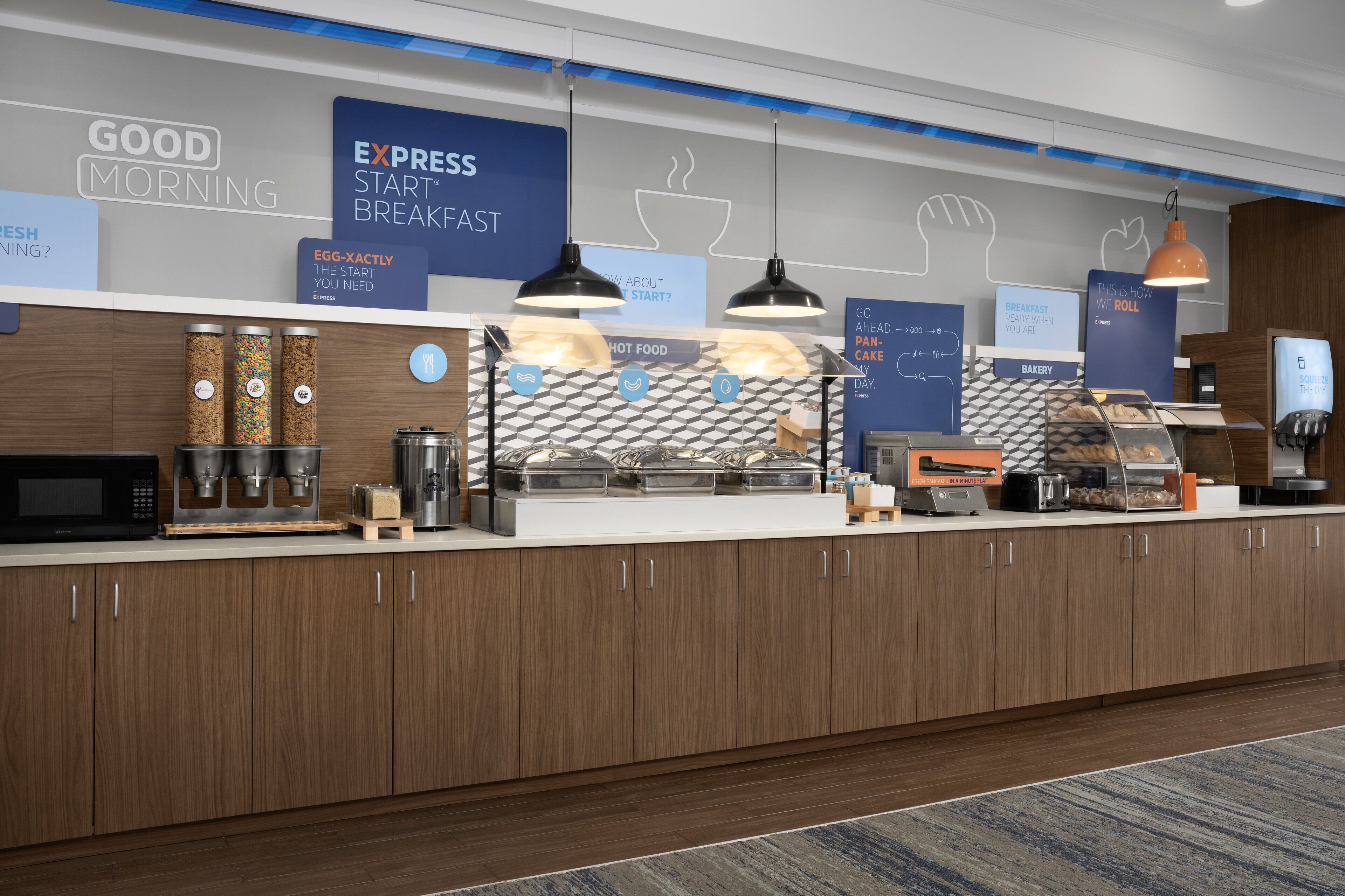 Uma área de café da manhã moderna com máquina de café, dosadores de temperos e uma seção de padaria.
