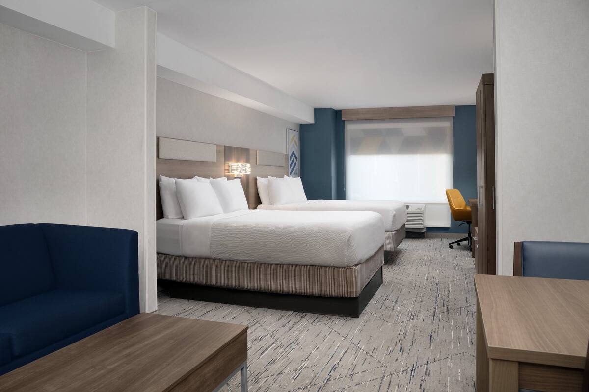 A hotel room with a large bed, a sofa, a desk, and a chair.