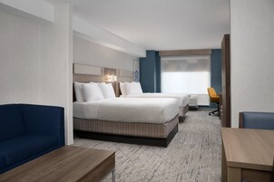 A hotel room with a large bed, a sofa, a desk, and a chair.