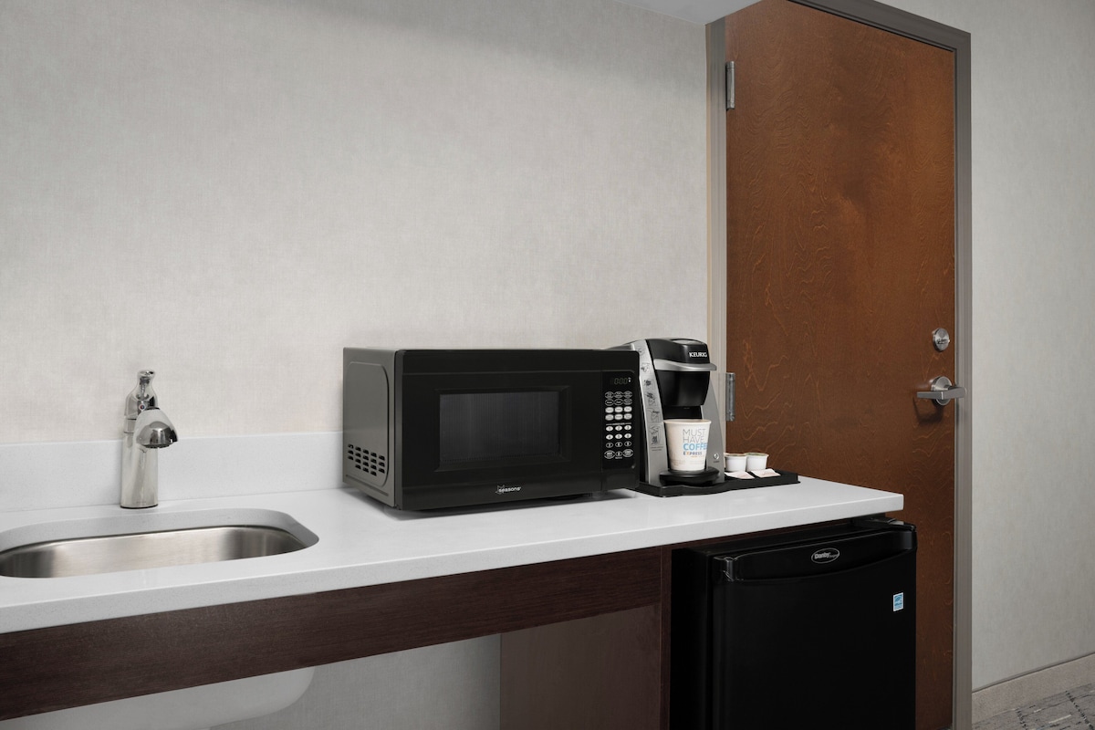 A kitchenette with a microwave, coffee maker, and dishwasher.