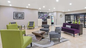 Una hall con poltrone verde e grigio, un divano viola e una scrivania della reception.