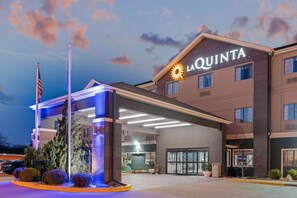A La Quinta hotel with a well-lit entrance, a flagpole, and a landscaped area with shrubs. - La Quinta Inn & Suites by Wyndham Ada (Ada)