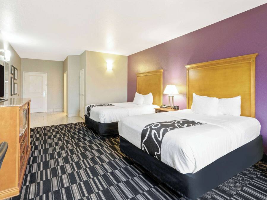 Une chambre d’hôtel avec deux lits, un bureau et une télévision.