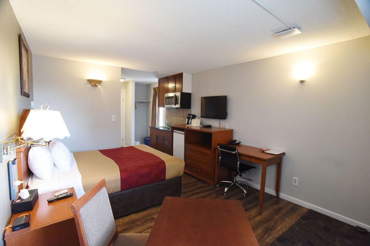 Une chambre d’hôtel équipée d’un lit, d’un bureau, d’une chaise et d’une kitchenette.