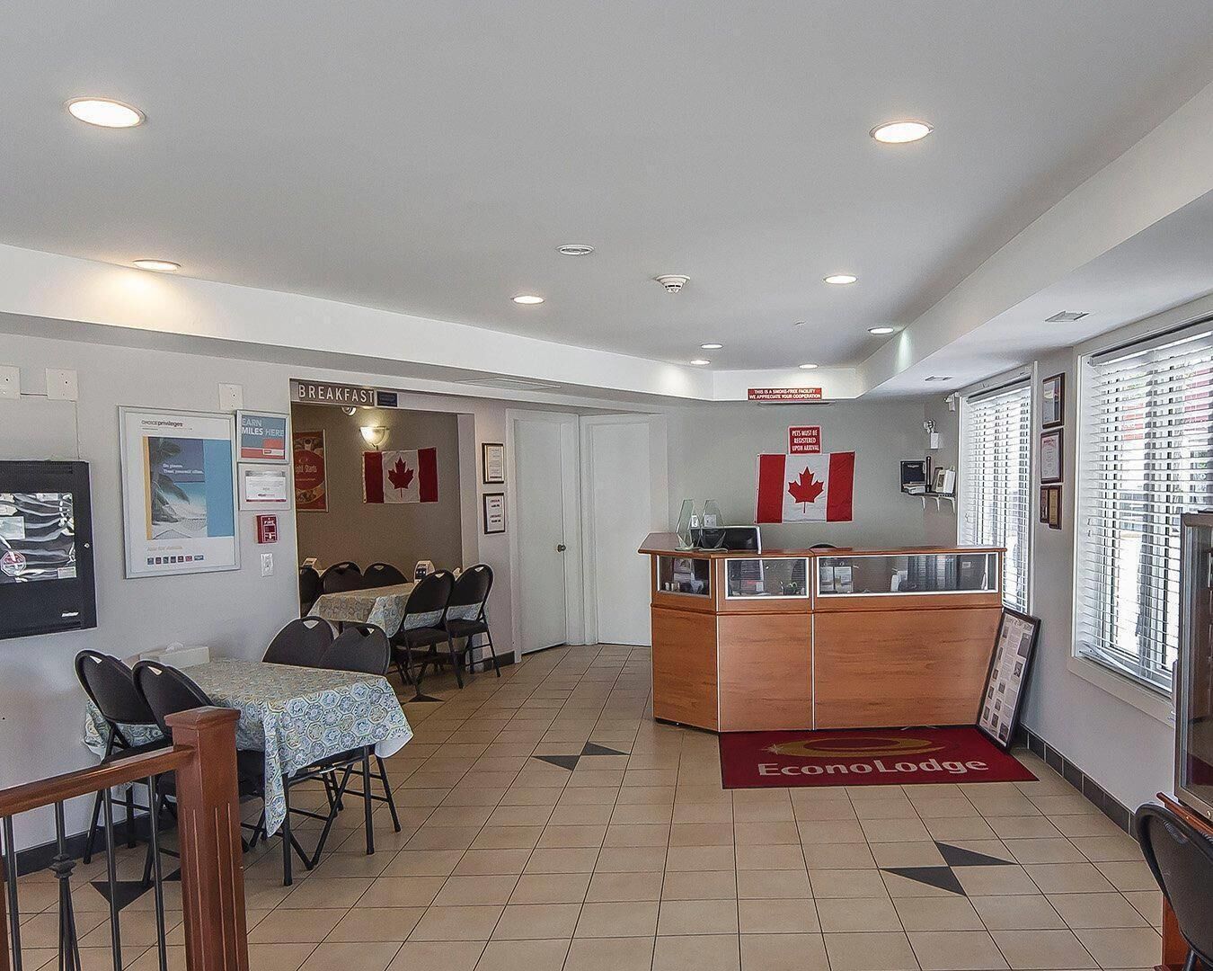 Un área de comedor con un letrero de desayuno, una bandera canadiense y una mesa de recepción.