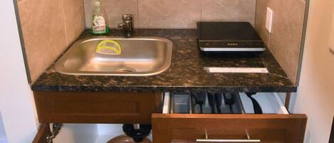 A compact kitchen with a stainless steel microwave, a sink, and a small countertop.