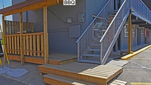 A wooden deck with a BBQ sign, a staircase, and a building facade. - Econo Lodge Inn & Suites Drumheller (Drumheller)