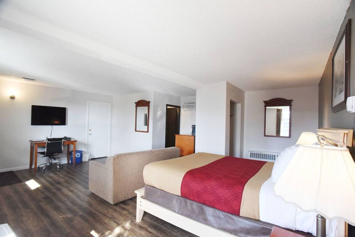 Una habitación de hotel con una cama, un escritorio, una silla, un televisor y una lámpara.