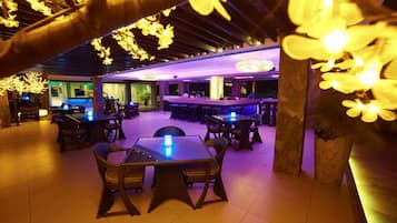 A restaurant with tables and chairs, a bar area, and decorative lighting.
