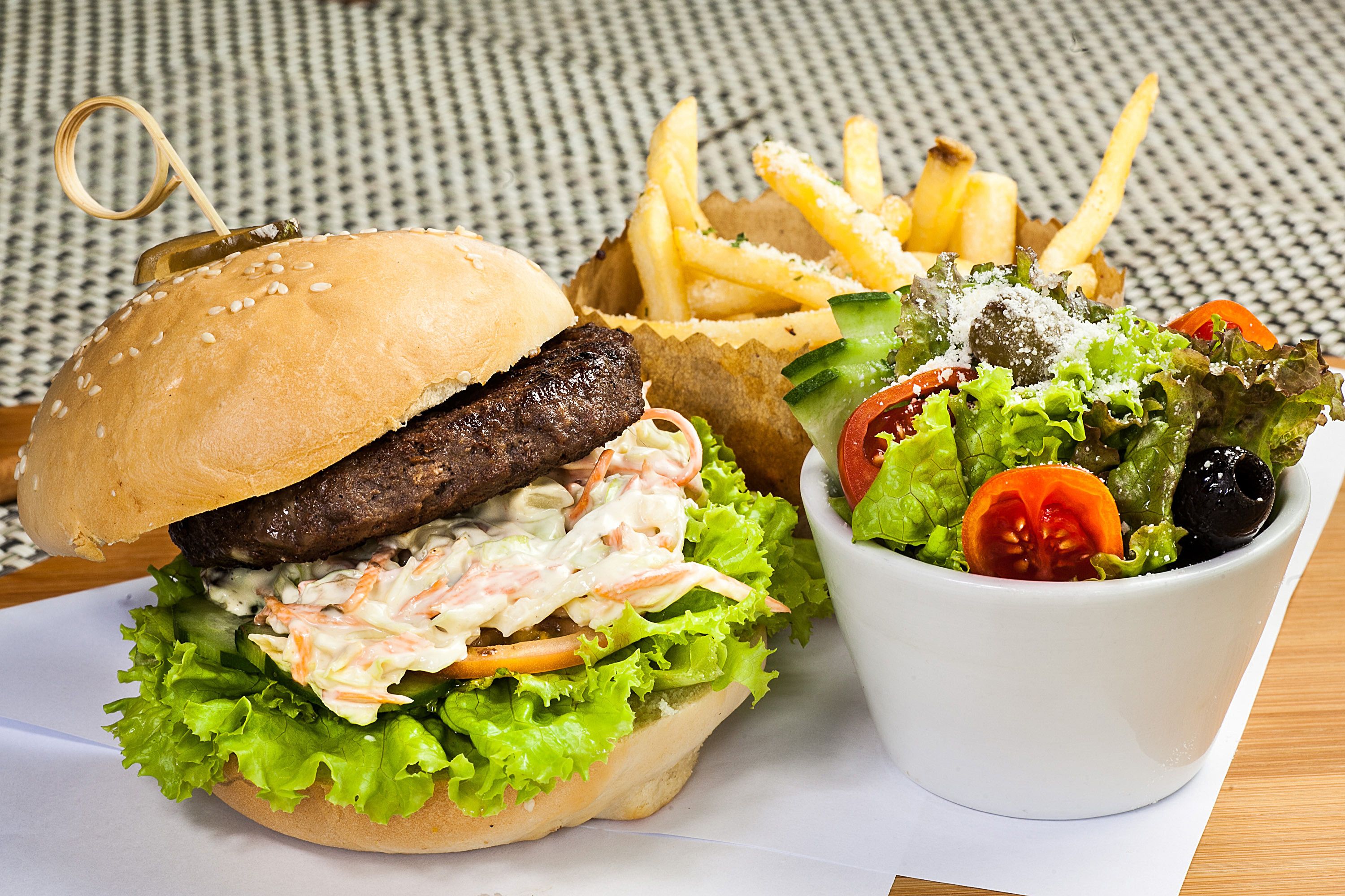 A burger with lettuce, tomato, and a side of fries and salad.