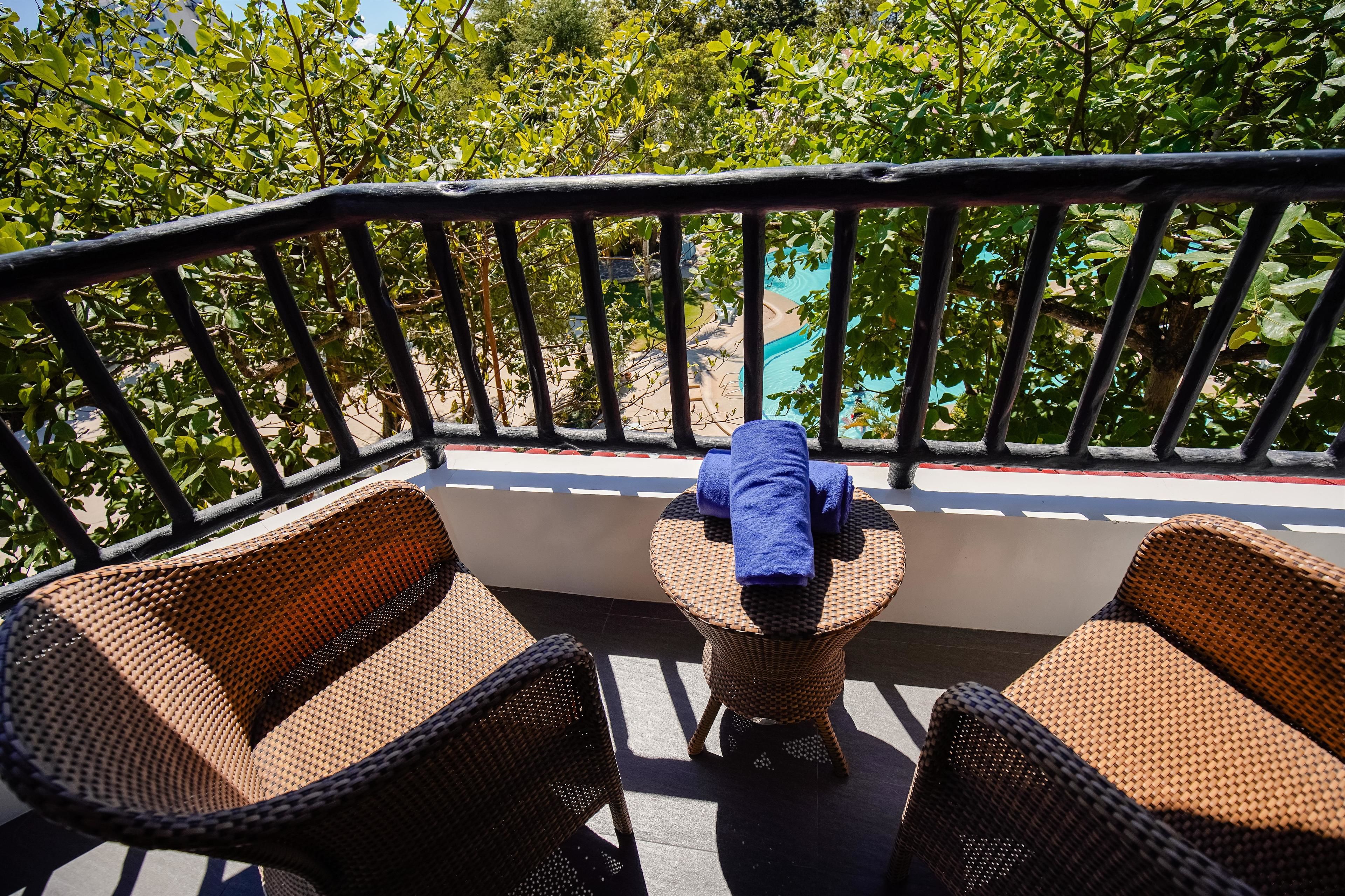 A balcony with wicker furniture and a view of a pool.