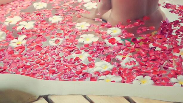 A person sitting on a bench with a wooden railing, surrounded by scattered flower petals. - Cebu White Sands Resort and Spa (Lapu-Lapu)
