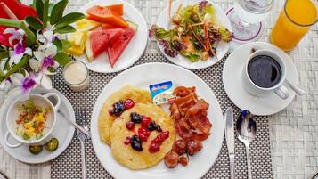 Una mesa de desayuno con platos de comida, una taza de café y un vaso de jugo de naranja.