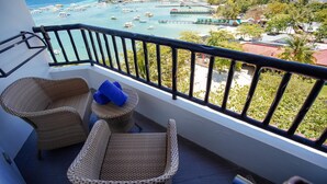 A balcony with wicker furniture and a view of a marina with boats and buildings. - Cebu White Sands Resort and Spa (Lapu-Lapu)