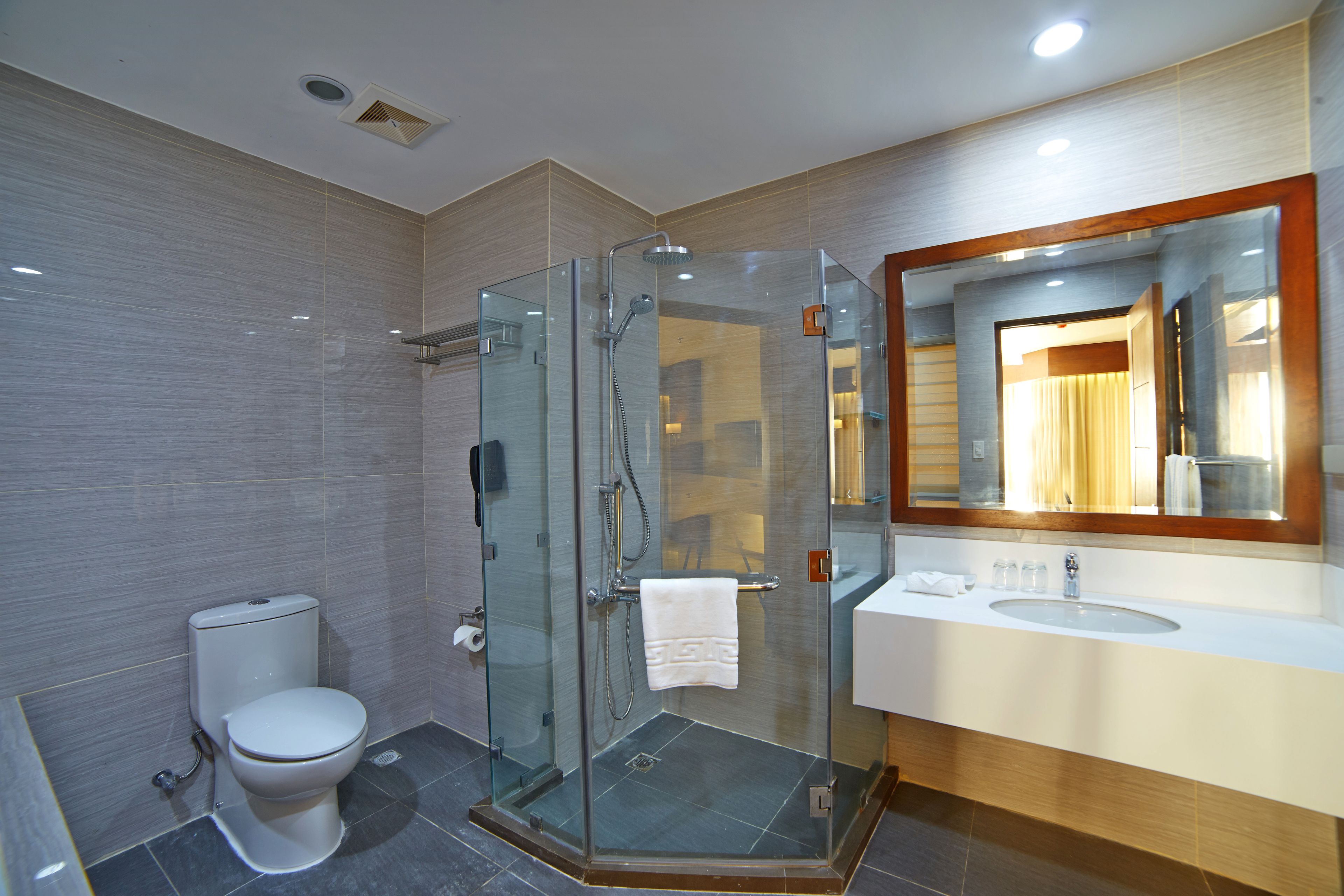 A modern bathroom with a glass-enclosed shower, a toilet, and a vanity with a mirror.