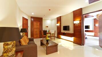 Habitación de hotel moderna con sofá, una mesa de centro, televisor y zona de comedor.