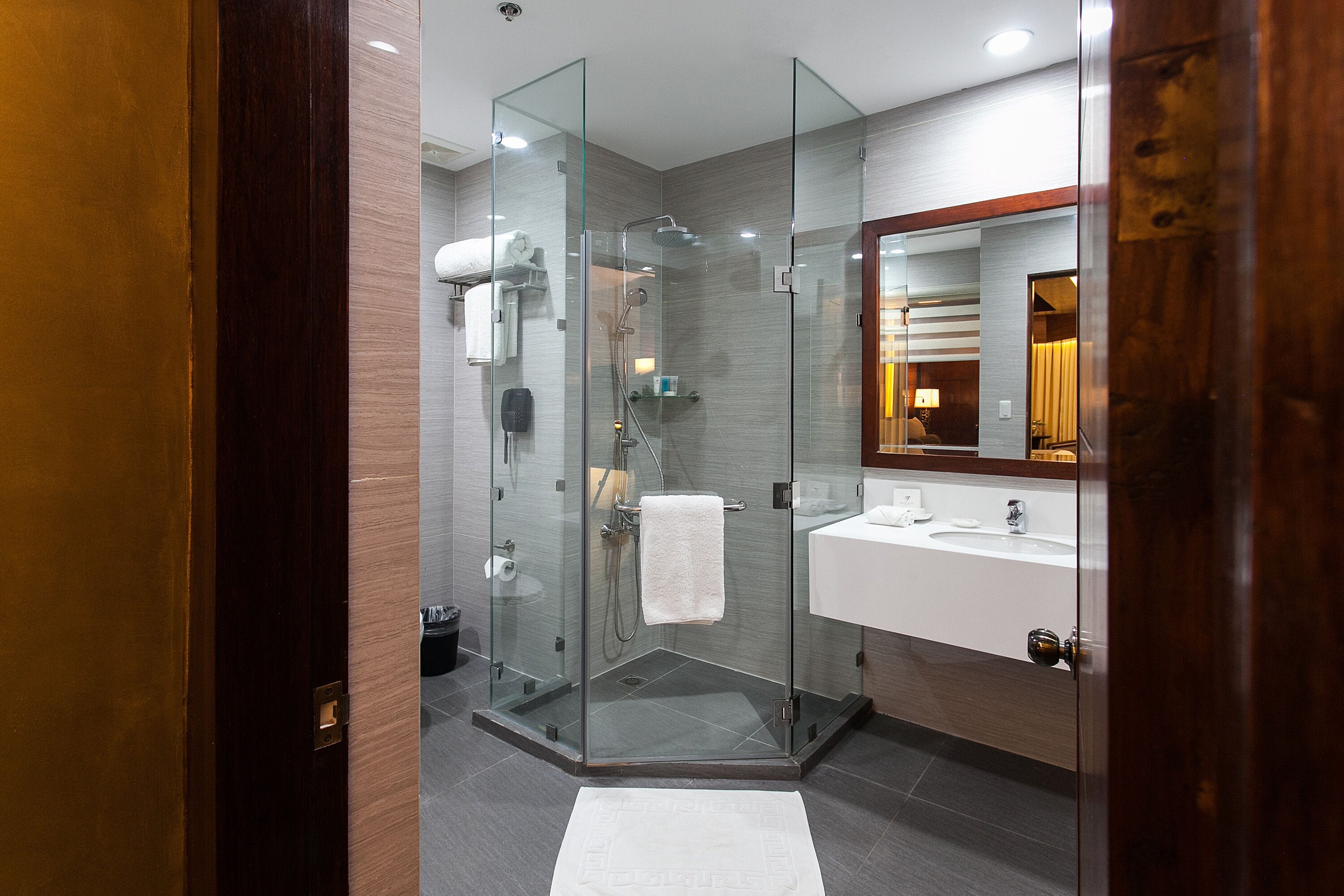 Un bagno moderno con doccia vetro, lavabo bianco e specchio con cornice in legno.