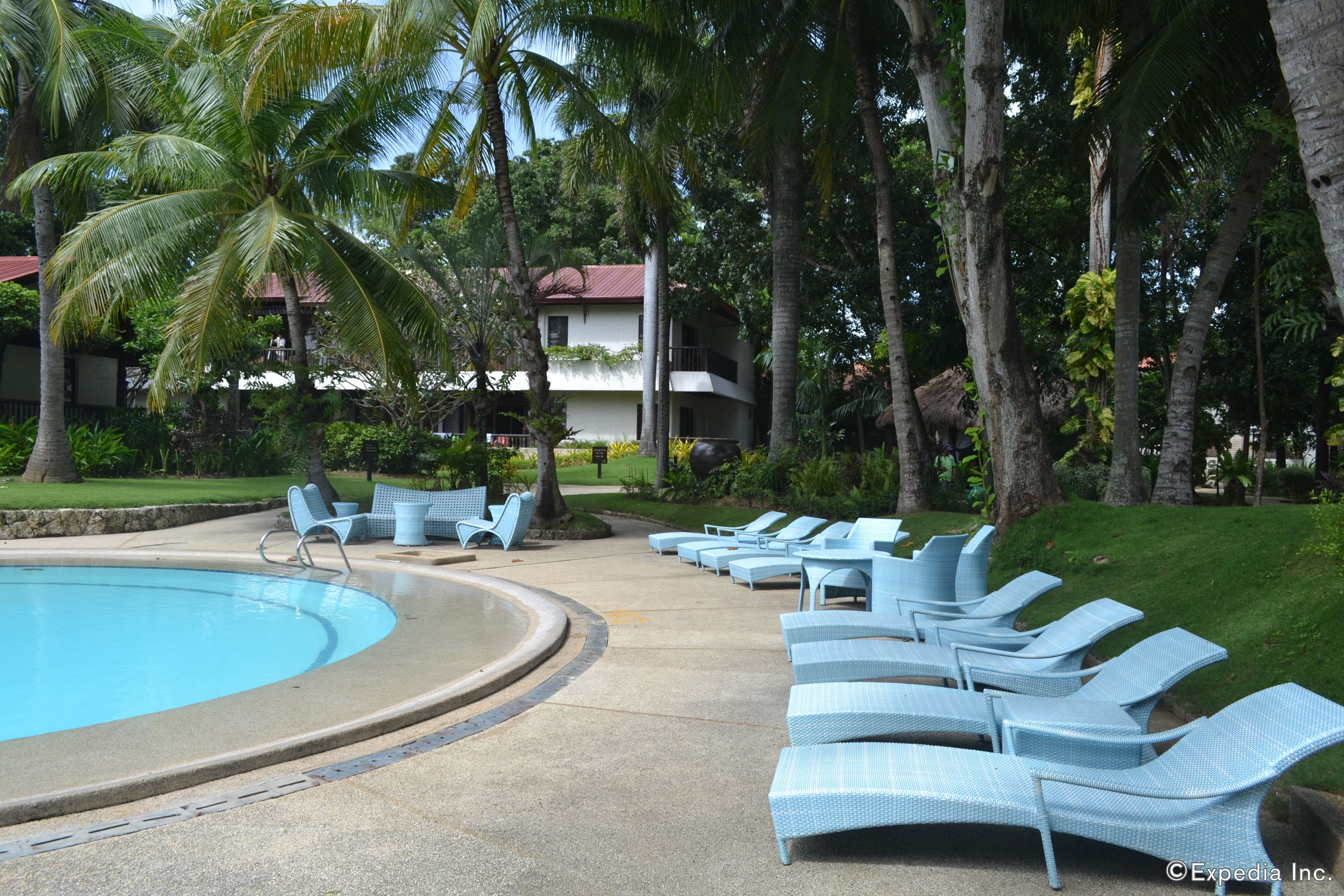 A pool area with lounge chairs and a building in the background.
