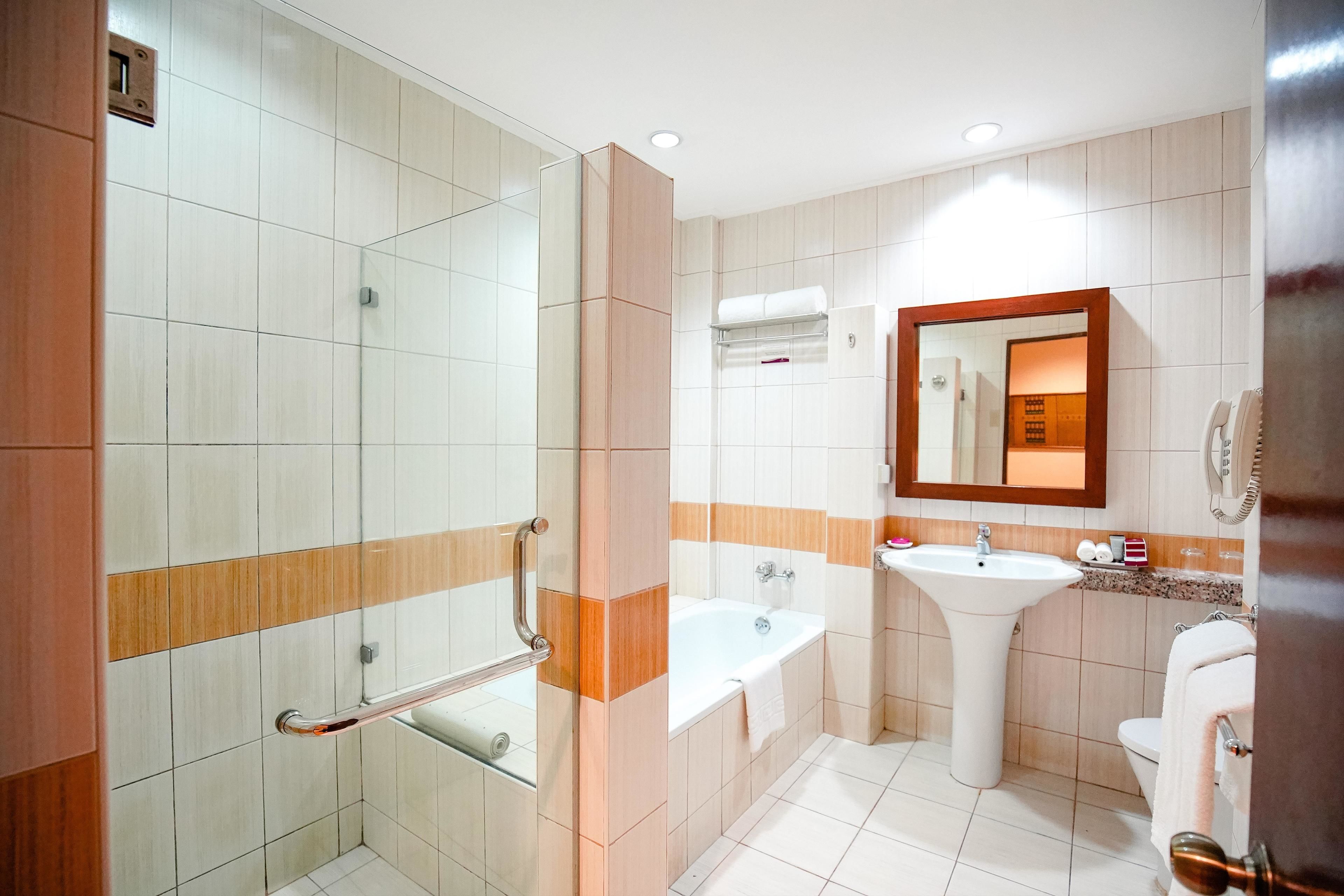 A modern bathroom with a glass shower enclosure, a bathtub, a sink, and a toilet.