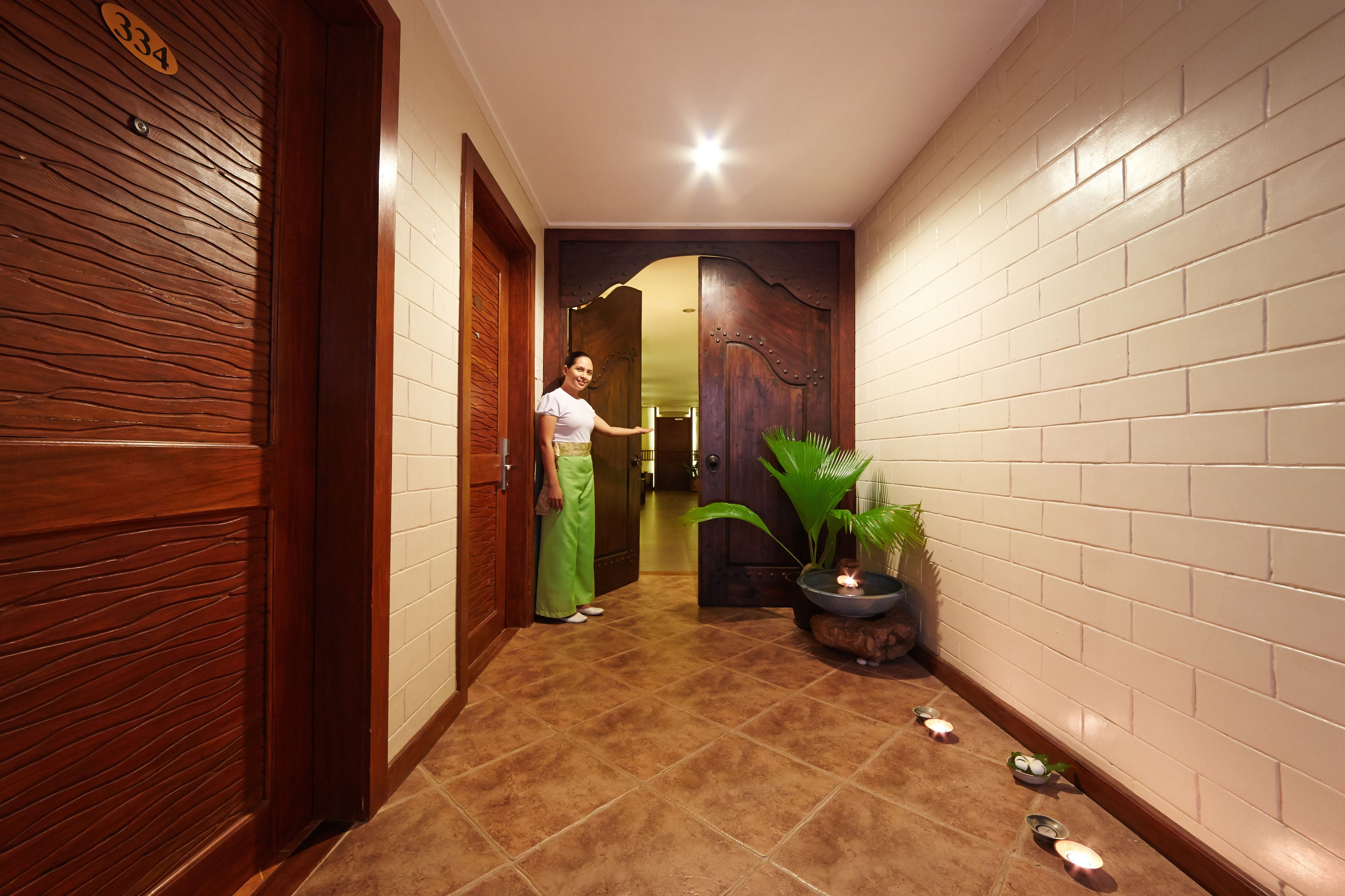 A hallway with a wooden door labeled "334", a potted plant, and a tiled floor.