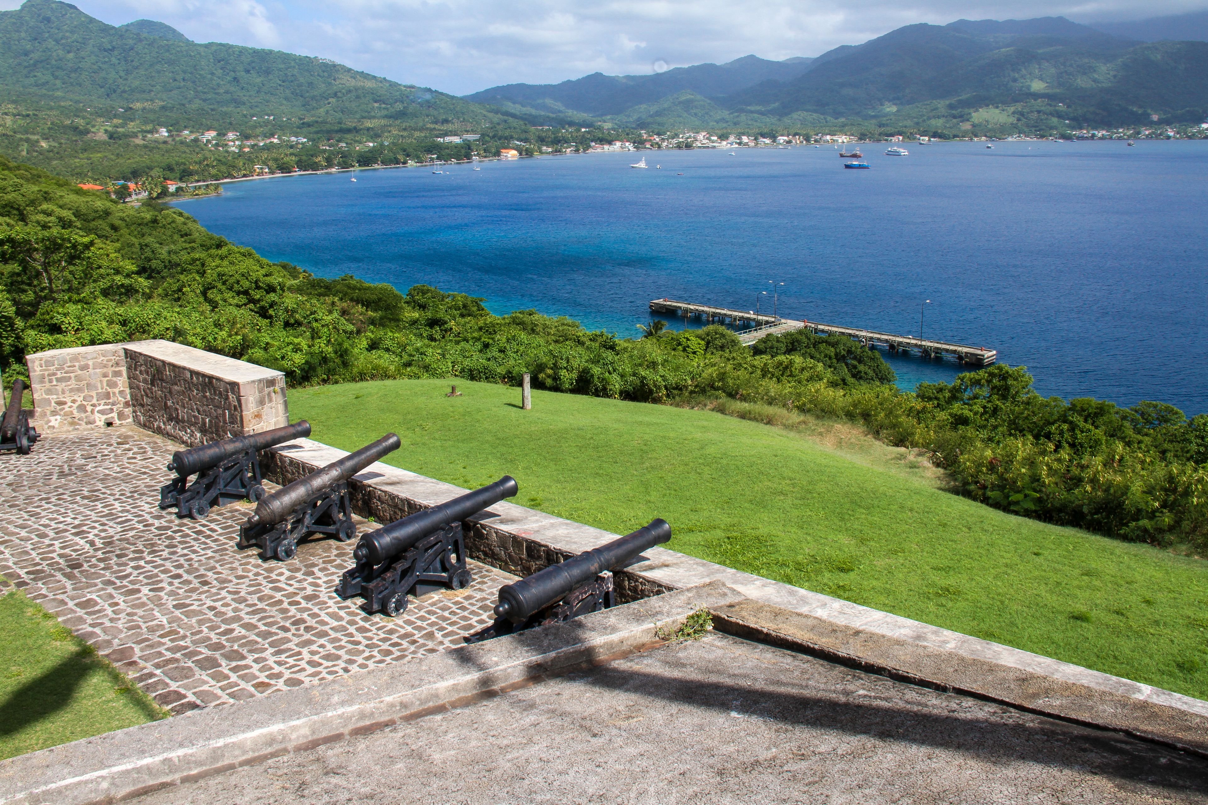 A coastal view with a grassy area and a stone structure with cannons.
