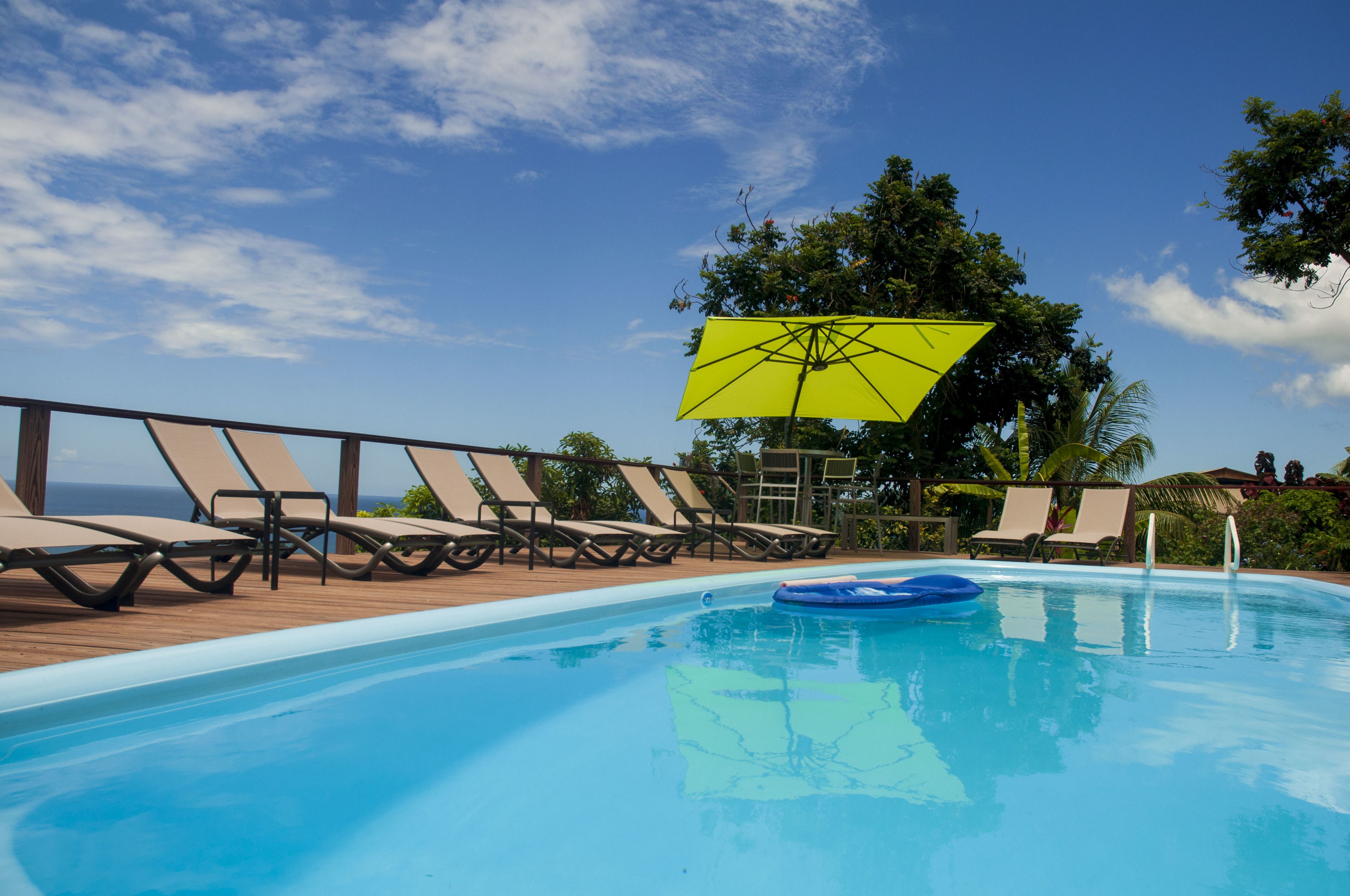 A pool area with lounge chairs and a yellow umbrella.