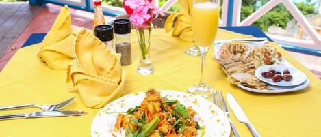 Una mesa dispuesta con comida, incluyendo un plato de alimentos, un vaso de jugo de naranja y una botella de agua, sobre un mantel amarillo.