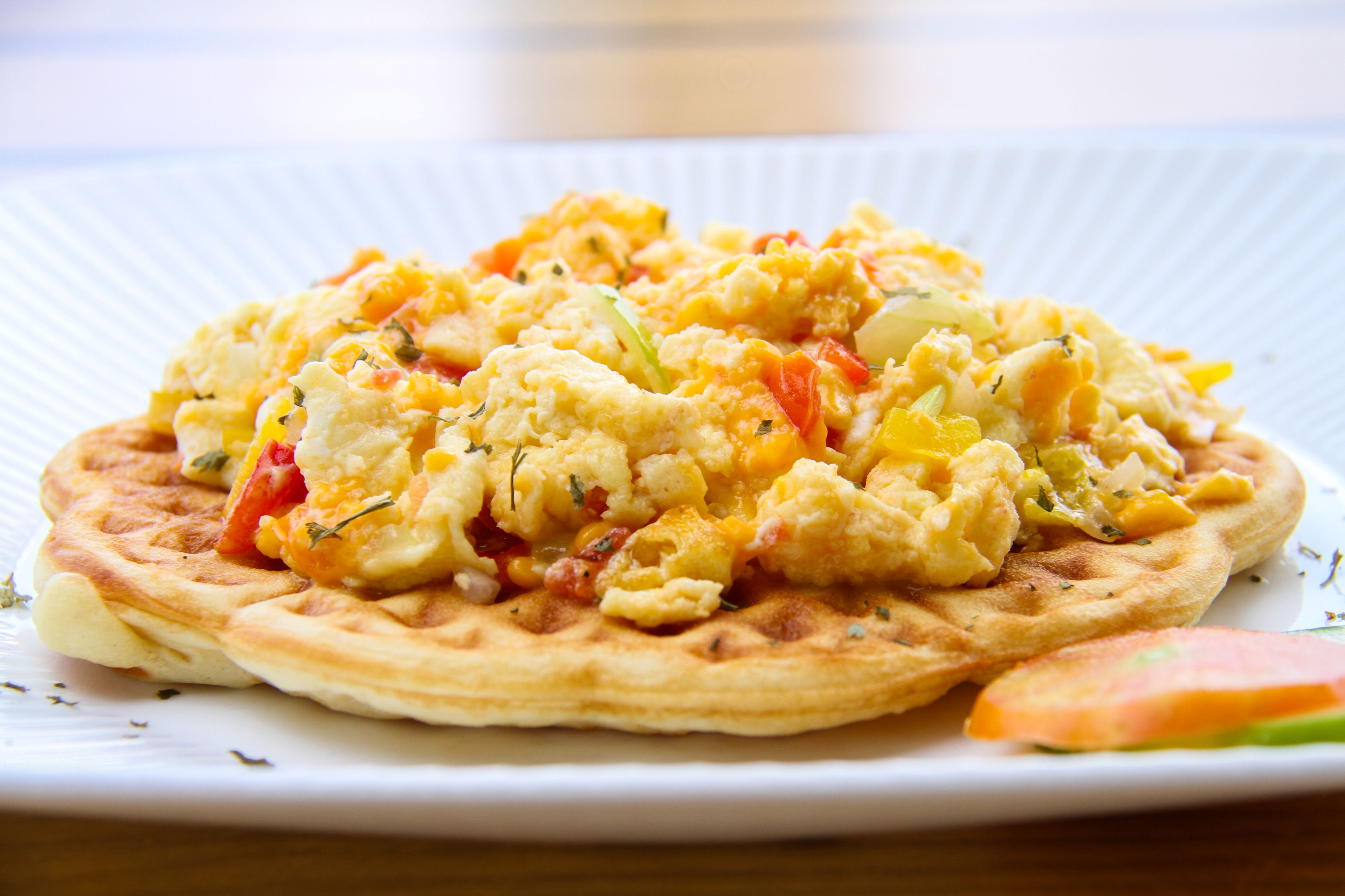 Un plato de huevos revueltos con verduras sobre un plato blanco.