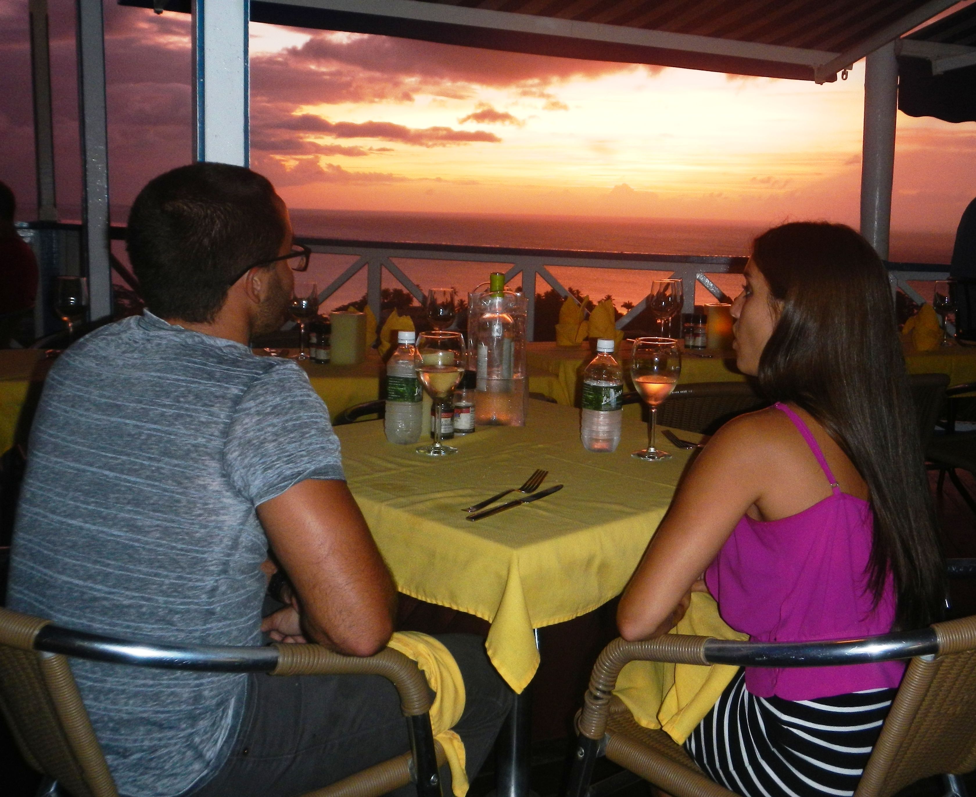 Una pareja cenando en una mesa con vista al atardecer.