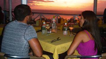 Una pareja cenando en una mesa con vista al atardecer.