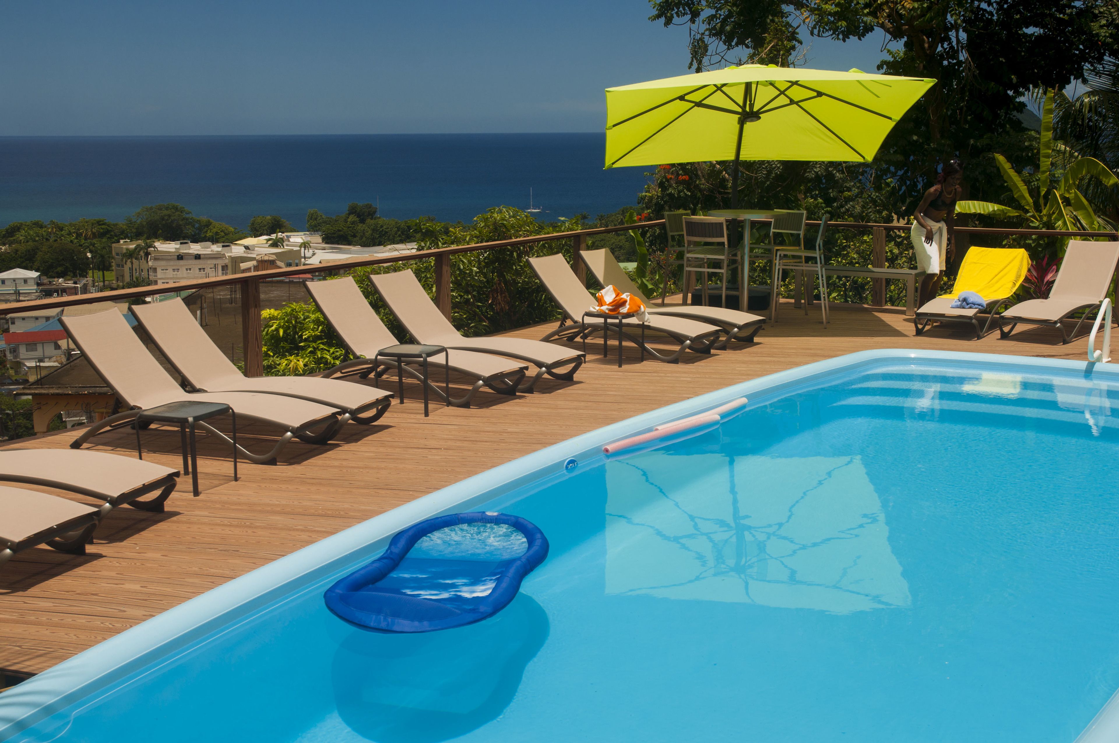 A poolside area with lounge chairs, a yellow umbrella, and a view of the ocean.