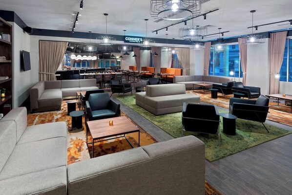 Un moderno vestíbulo de hotel con zonas de estar, un bar y un restaurante llamado 'CONNER'S'.