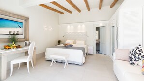 A modern bedroom with a bed, bedside table, chair, and a desk with a chair. - Forte Village Resort - Il Borgo (Pula)