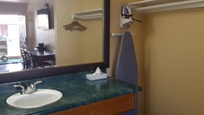 A bathroom with a sink, mirror, and towel rack. - American Regency Inn (Williams)