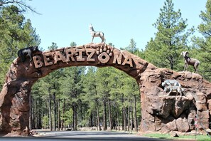 Un gran arco de roca con las palabras "BEARIZONA" y esculturas de animales, incluyendo un oso, un lobo y un carnero bighorn.