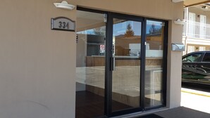 A building entrance with a glass door, a 'No Smoking' sign, and a 'Pull' sign. - American Regency Inn (Williams)