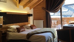 Een gezellige slaapkamer met een houten plafond, een bed met witte lakens en bruine kussens, een nachtkastje en een raam met gordijnen.
