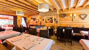 Een restaurant met houten wanden, hartvormige decoraties en gedekte tafels.