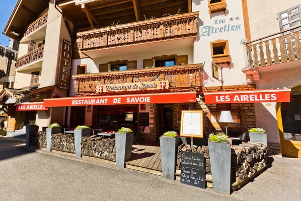 Un restaurante llamado 'Restaurant de Savoie' con terraza y un letrero que muestra el menú.