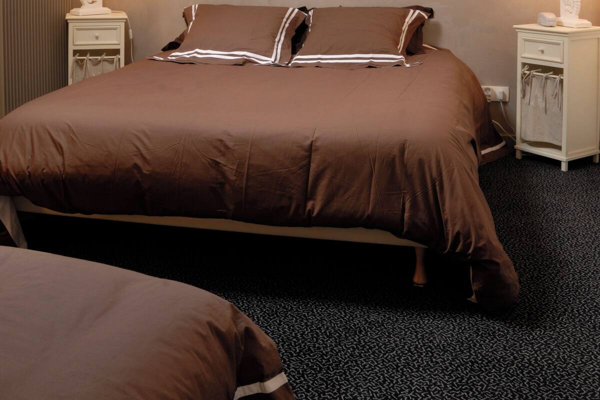 Une chambre à coucher avec un grand lit, deux tables de chevet avec des lampes, un radiateur et une lucarne.