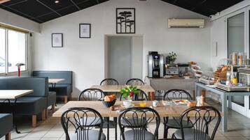Un comedor con una mesa de madera, sillas negras y una zona de estar con sofás negros.