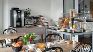 Un bufé de desayuno con diversas opciones de comida, una máquina de café y mesas dispuestas.