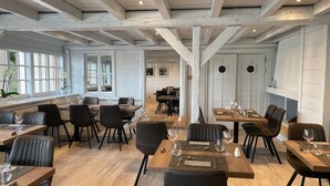 A restaurant with wooden tables and chairs, large windows, and a high ceiling with exposed beams. - Logis Hôtel Annecy Nord / Argonay (Argonay)