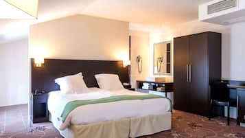 Habitación de hotel con una cama grande, mesitas de noche, un escritorio, un armario y un baño con espejo y toallero.